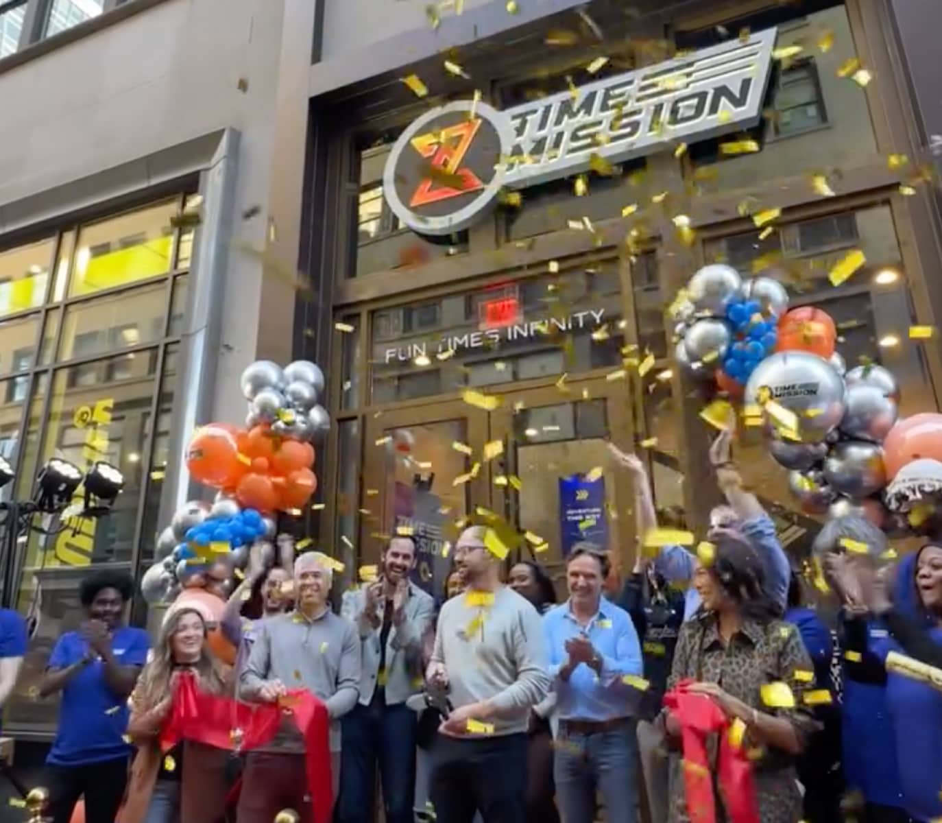 A group of people celebrate outside a building with a 