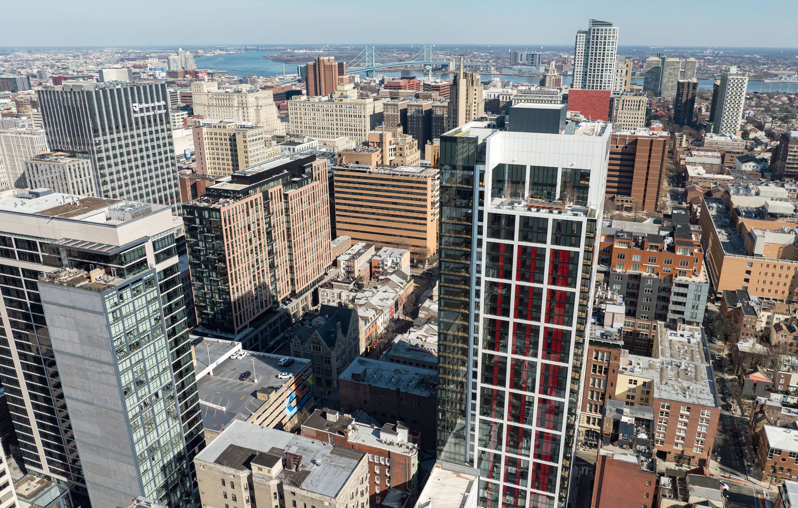 Aerial view of a cityscape with modern skyscrapers, historic buildings, and a river in the background. The scene conveys a bustling urban environment.