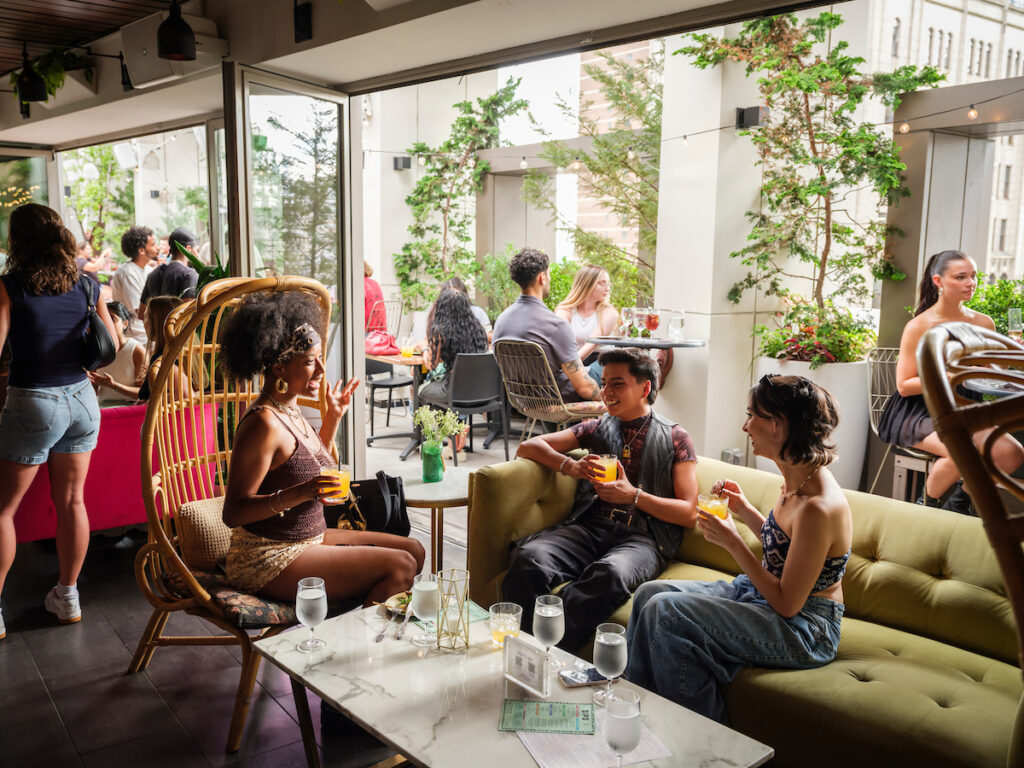 3 young adults sitting at an indoor outdoor lounge.