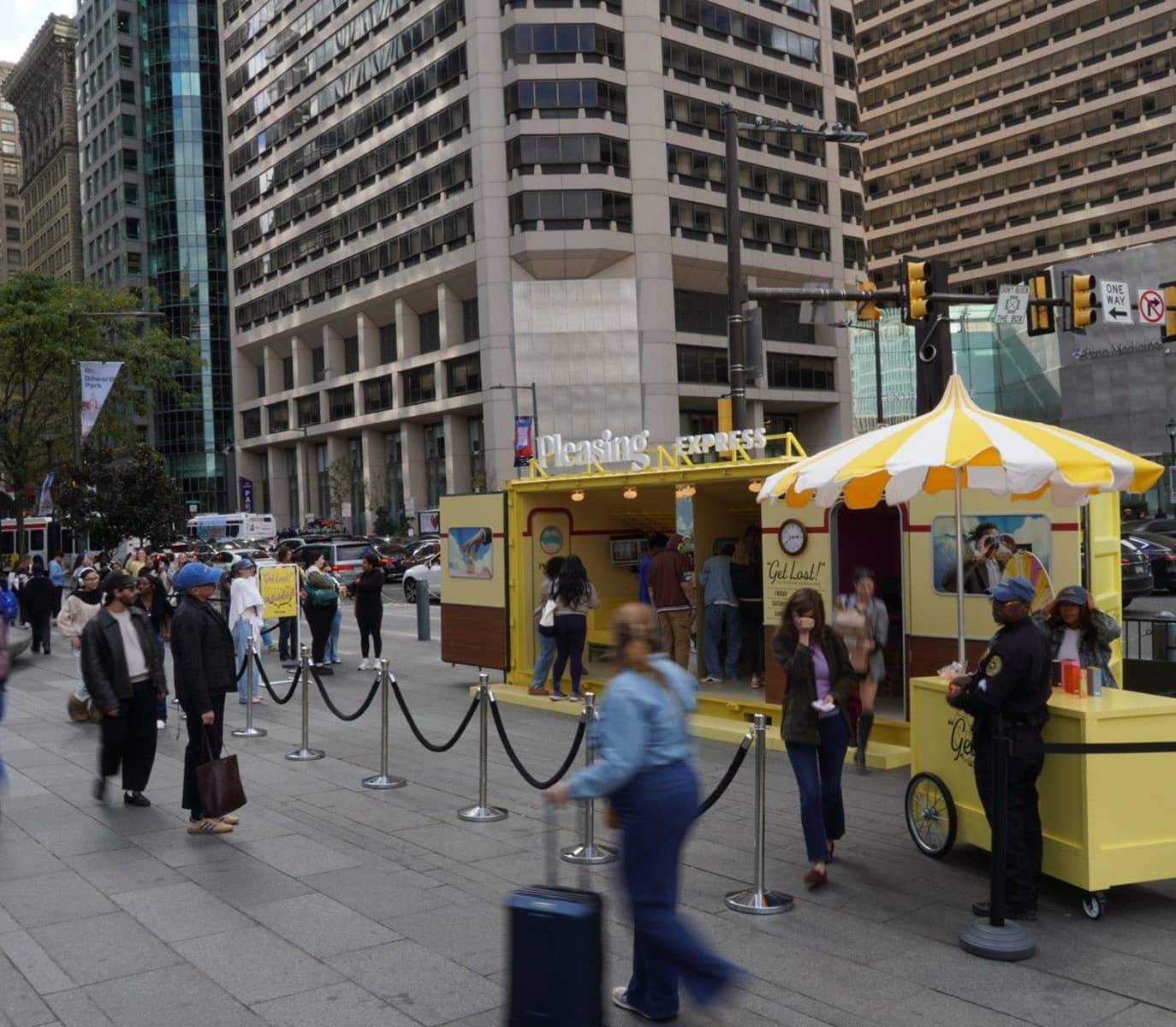 A bustling urban scene with people gathered around a yellow pop-up stand labeled 
