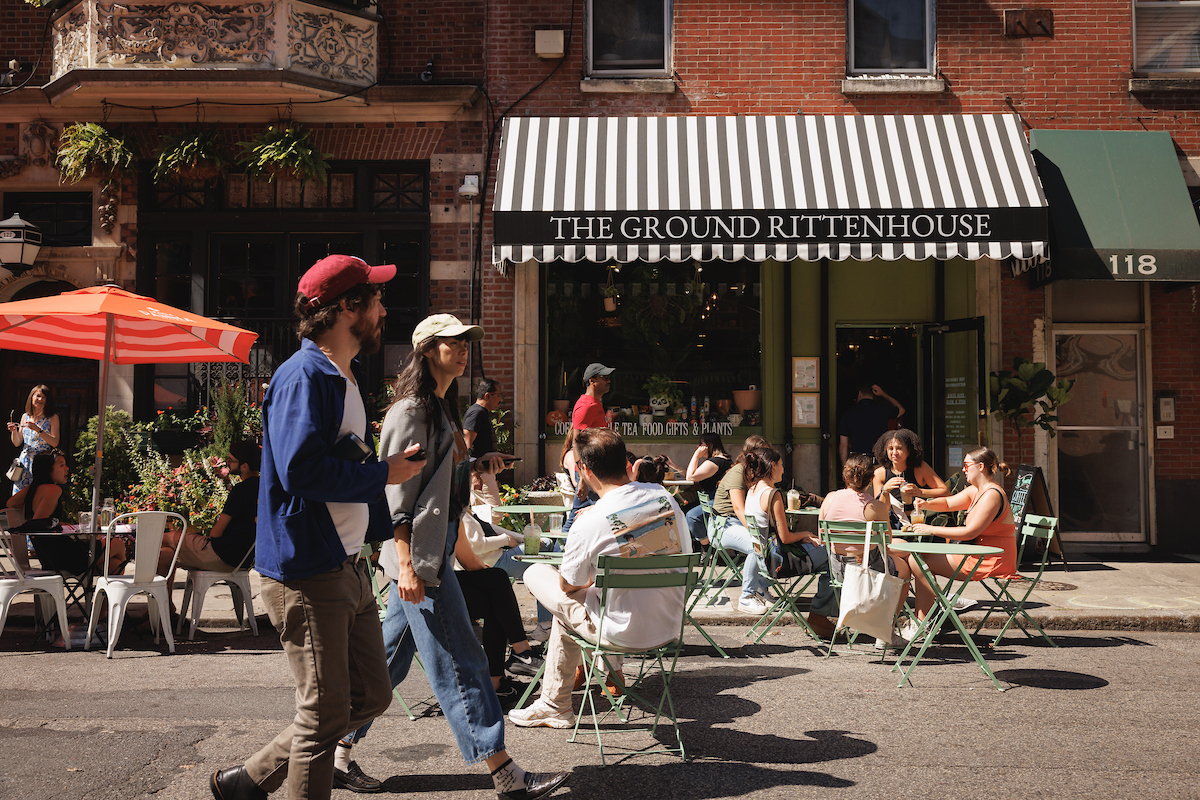 People walking and sitting at tables in front of the Ground cafe