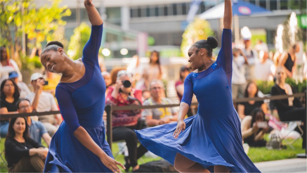 professional dancers in navy blue dresses performing in front of an audience outdoors.