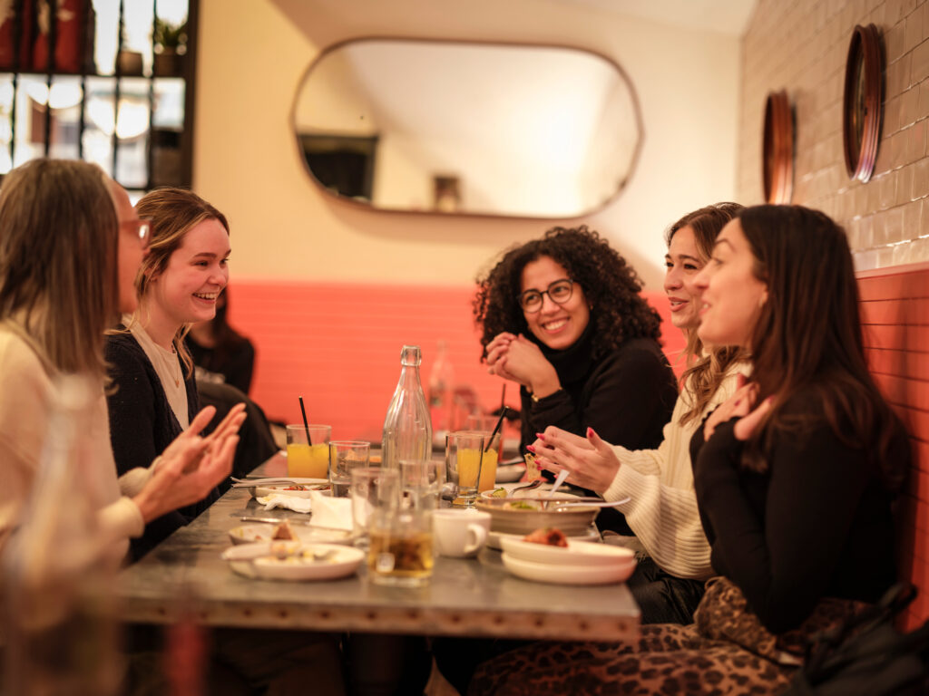 Women sitting at a table inside of a restaurant enjoying a meal.