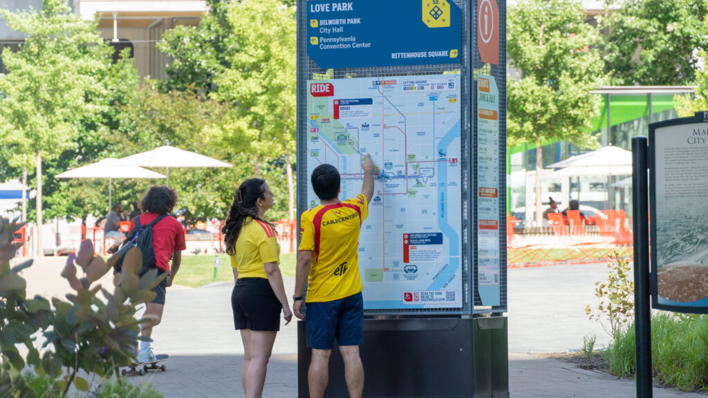 People looking for directions on the wayfinding map at Love Park.