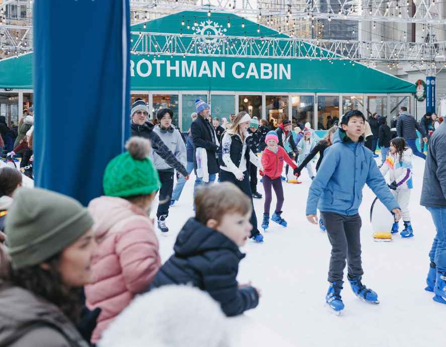 Crowded ice rink in philadelphia with children watching from the sideline.
