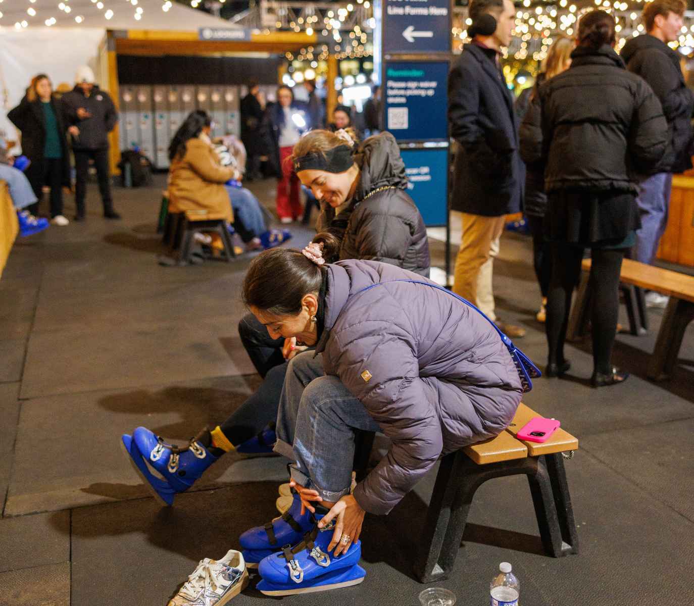 Two women putting ice skates on.