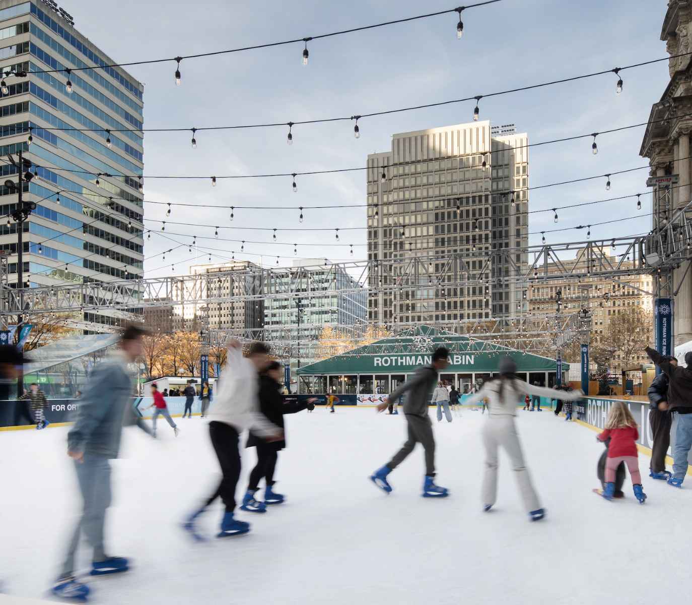 People ice skating fast and also a child on an assisted penguin