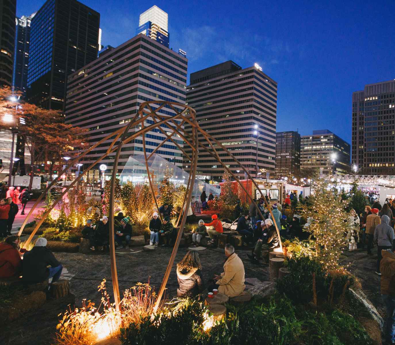 Wintergarden on the greenfield lawn lit under the night sky with people sitting int the space.