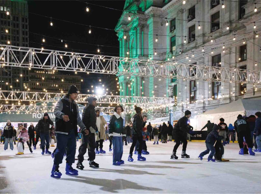 People skating at the Rothman Orthopaedics Ice Rink in Dilworth Park at night outside of Philadelphia's City Hall.